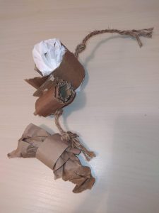Jouet suspendu composé de rouleaux de carton reliés par une corde et garnis de papier.